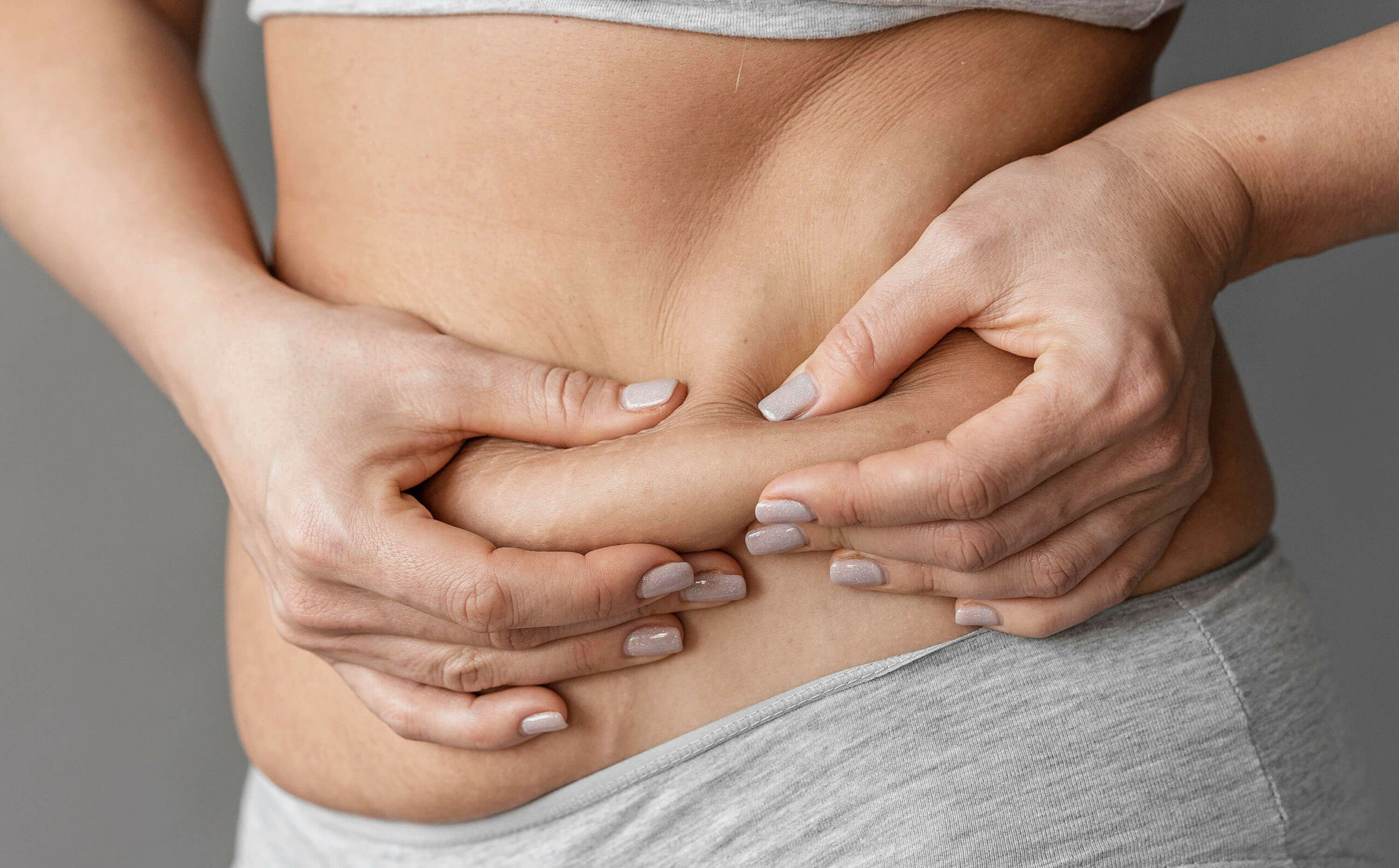 A woman pinching the side of her stomach.