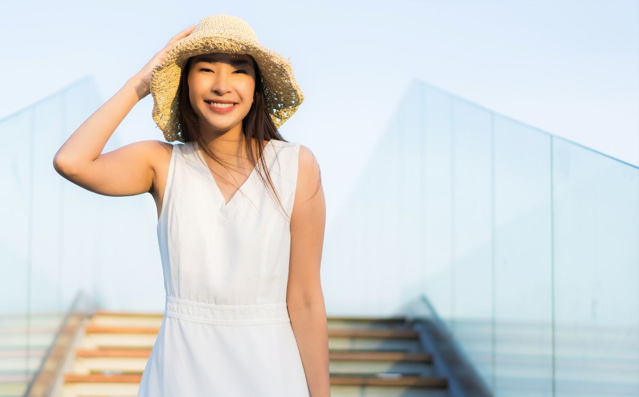 A woman is outdoors, wearing a sunhat to protect herself from the sun.