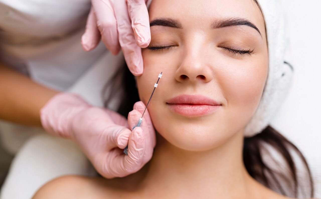 A woman smiling as a surgeon prepares to perform a traditional face lift, showcasing a professional and reassuring consultation.